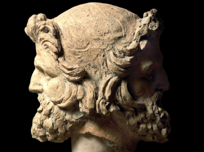 sculpture bust of the ancient Roman god Janus with two faces in the same head looking opposite directions on a black background